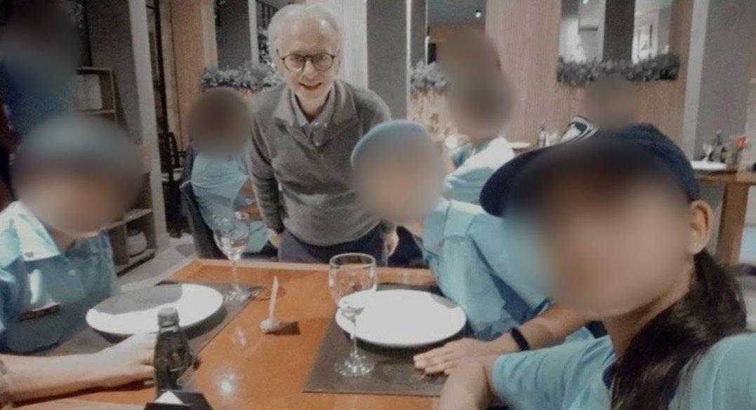 Alcides Madalozzo, sorridente, à mesa com guardas mirins uniformizados num jantar