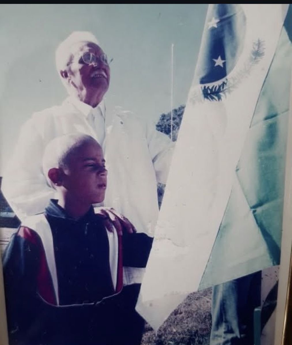 Seu Barros com um guarda mirim, diante da Bandeira Nacional